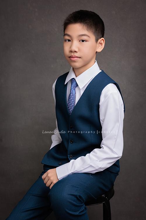 圻和同學們即將舉辦一場音樂會，身為管樂團的一員圻吹奏的是豎笛，換上西裝的圻多了份帥氣與沉穩，鏡頭裡的他自信而有氣質，這張是圻坐在椅子上很沈穩地看著鏡頭的音樂會相片！