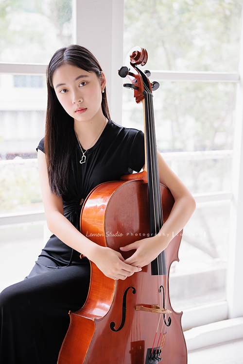 就讀高中音樂班的樂&妤，為了要辦的提琴音樂會，特地來拍攝音樂會寫真，兩人不僅默契十足，更散發著溫柔而有氣質的光彩，這張是樂坐在窗邊雙手抱著大提琴、酷酷地看著鏡頭！很美的一張音樂會寫真照！