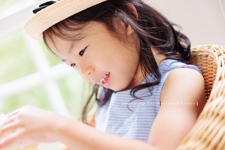 Jess媽一家第三次來拍照，這次是為了紀念雅滿四歲的時光，一家人總是自然又自在，照片裡流露出的，是日常中最真實舒服的模樣，這張是雅穿藍色洋裝、頭戴帽子看著手上的花的可愛模樣！