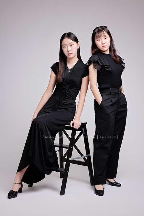 就讀高中音樂班的樂&妤，為了要辦的提琴音樂會，特地來拍攝音樂會寫真，兩人不僅默契十足，更散發著溫柔而有氣質的光彩，這張是樂坐在椅子上、妤站著、兩人都穿黑色系的衣服、兩人酷酷地看著鏡頭的音樂會寫真合照！