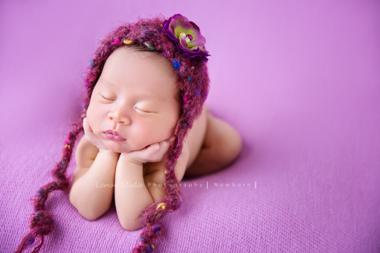 琄媽麻第二個寶貝的新生兒寫真，兩歲的小姊姊展現出滿滿的愛與呵護，小小的手輕輕撫摸著妹妹好有愛，而寶寶那努力撐著小頭的模樣，真是讓人一看就融化，怎麼看都看不膩，這張是寶寶趴在紫桃紅色的布上、頭上戴著紫色的帽子，兩手托著頭，睡著的可愛模樣，超級可愛的！