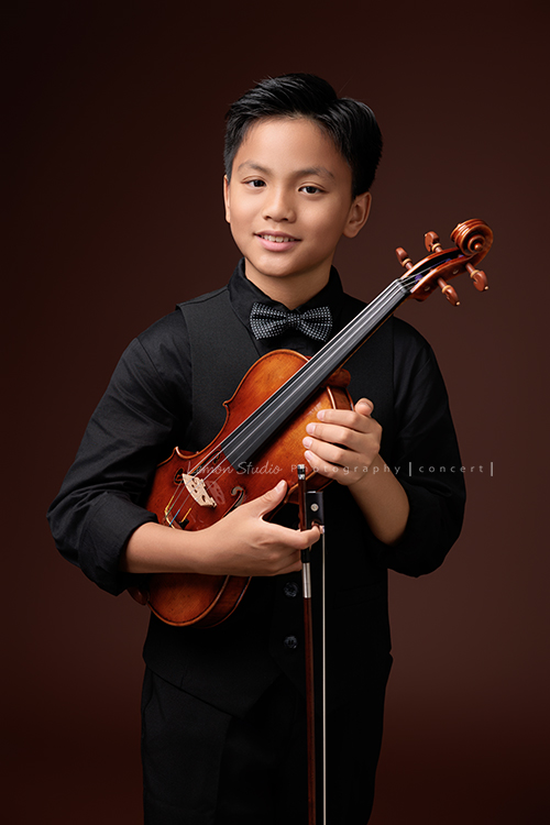 桀 & 恩兩兄弟一起來拍照，一位拍音樂寫真，一位拍個人紀錄，最後再並肩留下兄弟合照，這張是桀抱拿著提琴、面對鏡頭微笑的一張音樂會寫真！