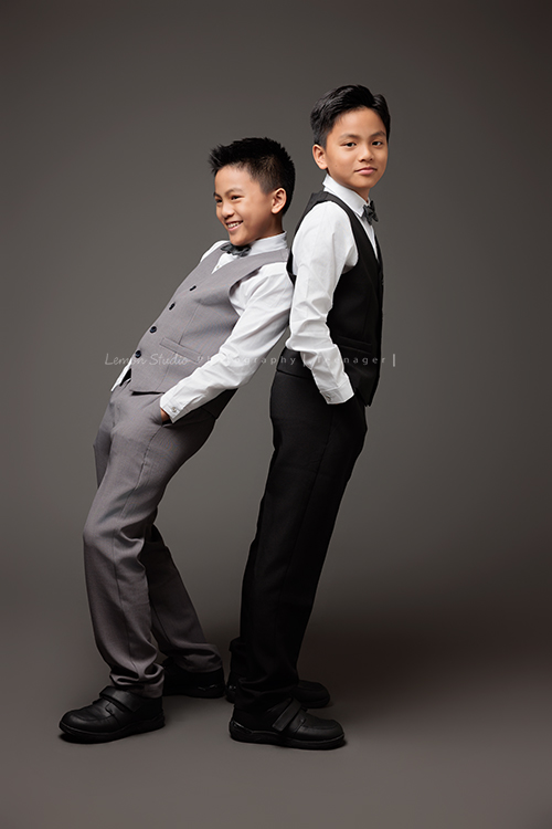 桀 & 恩兩兄弟一起來拍照，一位拍音樂寫真，一位拍個人紀錄，最後再並肩留下兄弟合照，這張是桀 & 恩兩人各穿著不同顏色的西裝背靠著背、兩人手放口袋，恩笑得很開心好像在玩沒有看鏡頭，桀看著鏡頭微微地笑的一張兄弟兩人的寫真合照！