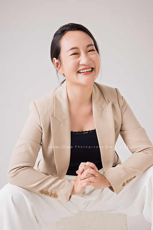 羌虎跨域生活創辦人南雁來拍照，這張是南雁坐在箱子上，穿高跟鞋、兩腳跨開、很陽光地看著鏡頭笑得很開心的形象照！