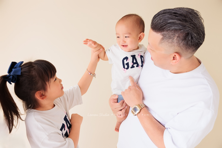 珈平媽麻一家第六次來拍照，這回多了一位新成員，櫟櫟當姊姊了，剛滿一歲的弟弟一舉一動都可愛得讓人融化，這張是爸拔抱著弟弟，姊姊和弟弟兩人可愛的互動的一瞬間的相片！