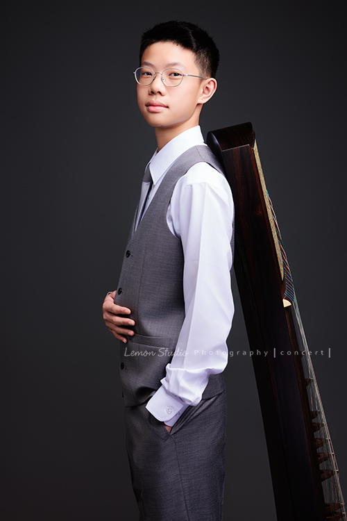 Benson帶著古箏走進鏡頭，穿上馬面裙的那一刻，彷彿穿越時空回到古代，同時又有如舞台上的模特兒般自信，一次拍下古韻與現代交織的獨特風格，這張是Benson穿上西裝背心、一手放口袋，背靠著古箏、看著鏡頭微笑的一張音樂會寫真！