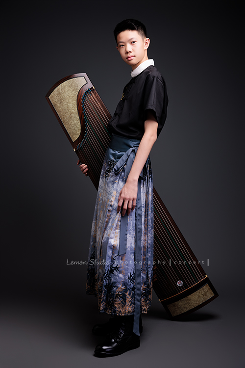 Benson帶著古箏走進鏡頭，穿上馬面裙的那一刻，彷彿穿越時空回到古代，同時又有如舞台上的模特兒般自信，一次拍下古韻與現代交織的獨特風格，這張是Benson穿著馬面裙、一手抱著古箏沈穩地看著鏡頭的全身音樂會寫真！