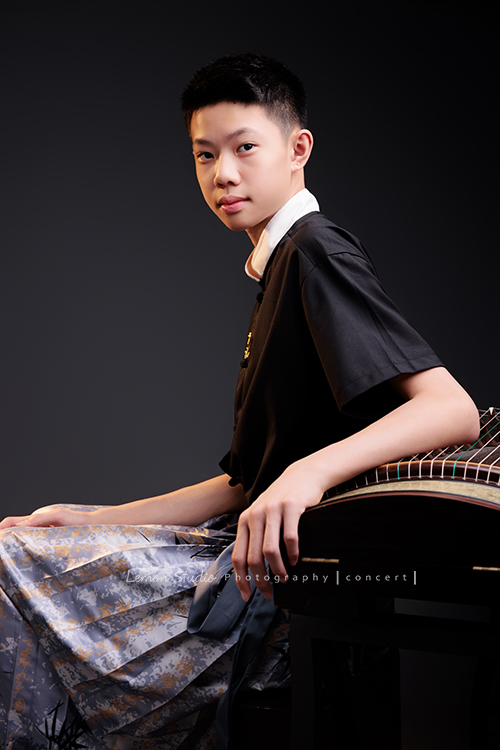 Benson帶著古箏走進鏡頭，穿上馬面裙的那一刻，彷彿穿越時空回到古代，同時又有如舞台上的模特兒般自信，一次拍下古韻與現代交織的獨特風格，這張是Benson穿著馬面裙、側身坐在古箏旁，一手放在古箏上，很沈穩地看著鏡頭、一張很有意境的音樂會寫真！