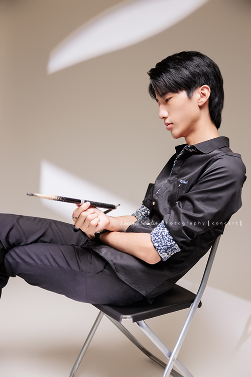 又高又有型的 Xavier前來拍攝音樂會寫真，他的專長是馬林巴木琴，手握鼓棒入鏡時，每一張都散發著時尚與帥氣的氣息，這張是Xavier坐在椅子上看著手中的鼓棒的音樂會寫真照！