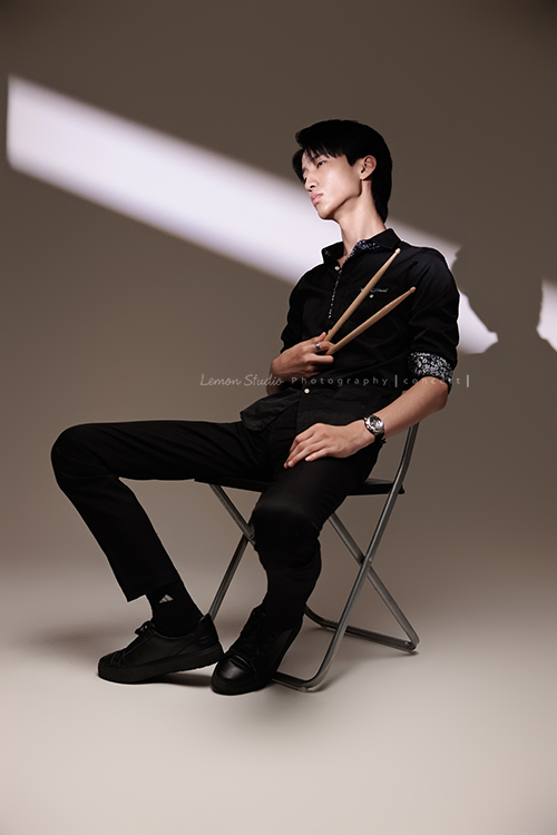 又高又有型的 Xavier前來拍攝音樂會寫真，他的專長是馬林巴木琴，手握鼓棒入鏡時，每一張都散發著時尚與帥氣的氣息，這張是Xavier坐在椅子上手拿著鼓棒沒有看鏡頭的音樂會寫真照！