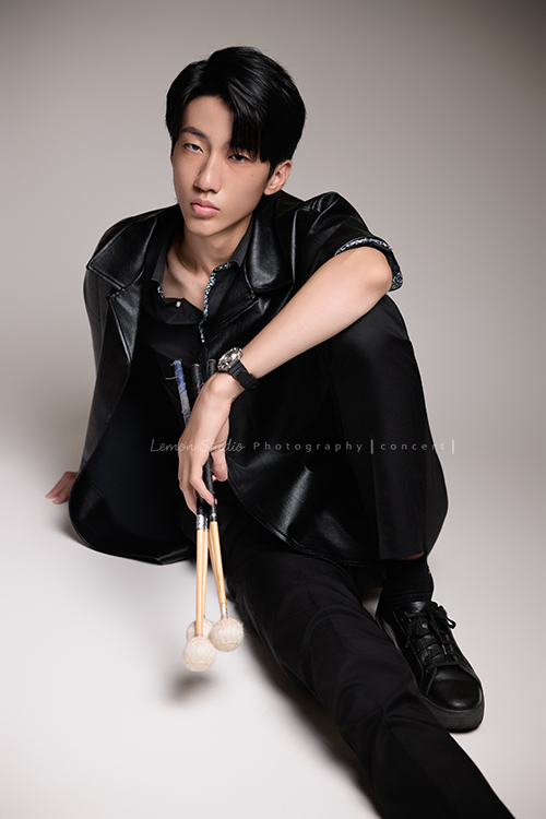 又高又有型的 Xavier前來拍攝音樂會寫真，他的專長是馬林巴木琴，手握鼓棒入鏡時，每一張都散發著時尚與帥氣的氣息，這張是Xavier坐在地上一手拿著鼓棒一手扶在地板上、酷且帥氣地看著鏡頭的音樂會寫真照！