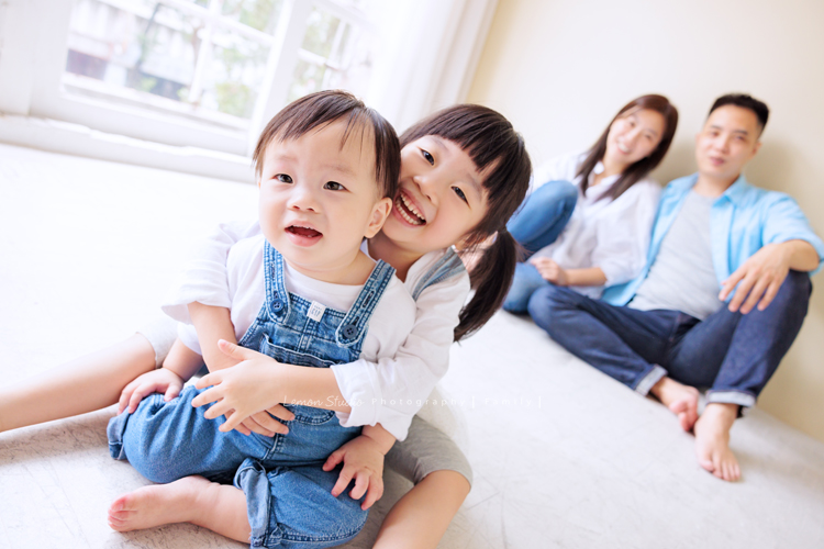 Ida媽麻一家第三次來拍照，四歲半和一歲半的姊弟倆，笑容與童趣洋溢，爸拔媽麻也陪著一起玩得很開心，這張是姊姊和弟弟坐在爸拔媽麻前方，姊姊抱著弟弟笑得很開心的可愛互動照！