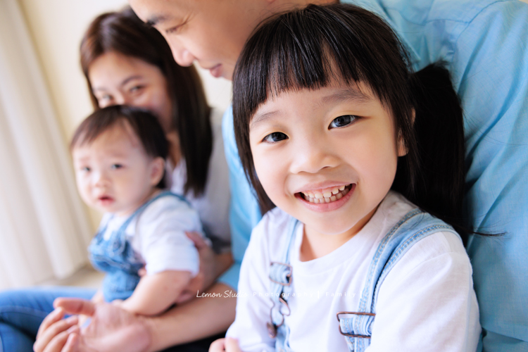 Ida媽麻一家第三次來拍照，四歲半和一歲半的姊弟倆，笑容與童趣洋溢，爸拔媽麻也陪著一起玩得很開心，這張是爸拔抱著姊姊坐在媽麻及弟弟的前面，姊姊看著鏡頭可愛地笑著的姊姊的特寫相片！