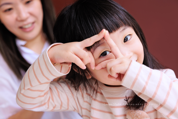Ida媽麻一家第三次來拍照，四歲半和一歲半的姊弟倆，笑容與童趣洋溢，爸拔媽麻也陪著一起玩得很開心，這張是姊姊兩隻手比出很可愛的框框的姿勢的一張很俏皮的姊姊的個人兒童寫真照！