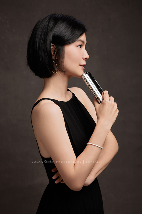 知名口琴演奏家衍華，近日為音樂形象照拍攝，緩緩展開她與音樂的對話，歷經無數舞台洗禮，屢獲殊榮並擔任評審的她，舉手投足間皆是樂音流動的痕跡，彷彿音符化形，翩然於鏡頭之中，這張是衍華身穿黑色的禮服側身沒有看鏡頭，一手拿著口琴放在下巴處，雖然沒有看鏡頭，卻是一張很美很有意境的音樂形象照！