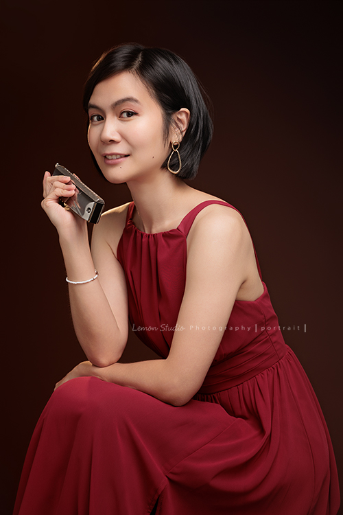 知名口琴演奏家衍華，近日為音樂形象照拍攝，緩緩展開她與音樂的對話，歷經無數舞台洗禮，屢獲殊榮並擔任評審的她，舉手投足間皆是樂音流動的痕跡，彷彿音符化形，翩然於鏡頭之中，這張是衍華身穿紅色的禮服側身坐在椅子上，手拿著口琴，看著鏡頭微笑的一張很美的音樂形象照！