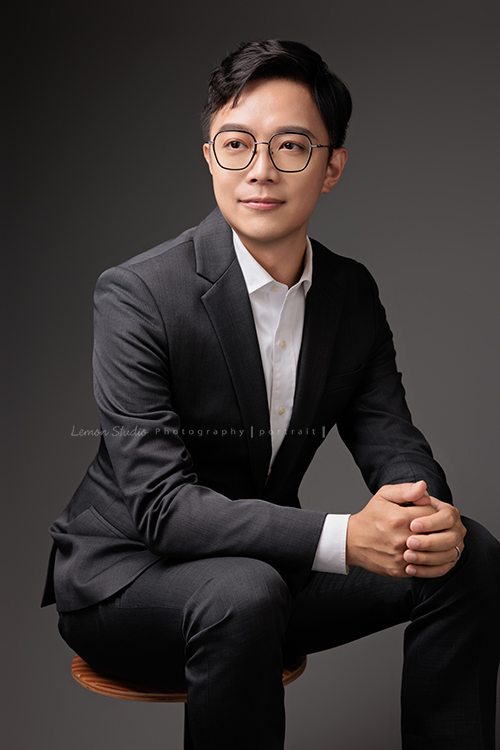 圓璽不動產專屬顧問團隊，以最真誠與專業的樣貌入鏡，每一位都展現出獨一無二的形象與風格，這是顧問Tim側坐在椅子上雙手互握，沒有看著鏡頭但很有fu的一張不動產顧問形象照！