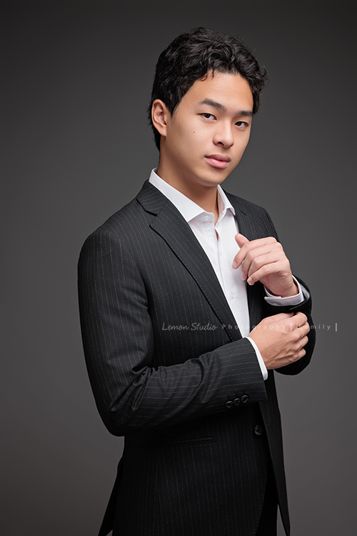 Cindy 媽麻一家來拍照，在美國念書的兒子瑋，帥氣又溫暖，一家人換上正式與休閒的服裝，每一張照片都記錄下最自然的互動與情感，這張是兒子瑋穿著西裝、一手拉著西裝手上的扣子，酷酷地看著鏡頭，是一張很帥氣的個人寫真！