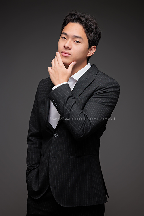 Cindy 媽麻一家來拍照，在美國念書的兒子瑋，帥氣又溫暖，一家人換上正式與休閒的服裝，每一張照片都記錄下最自然的互動與情感，這張是兒子瑋穿著西裝、一手放口袋、一手摸著臉，酷酷地看著鏡頭，是一張很帥氣的個人寫真！