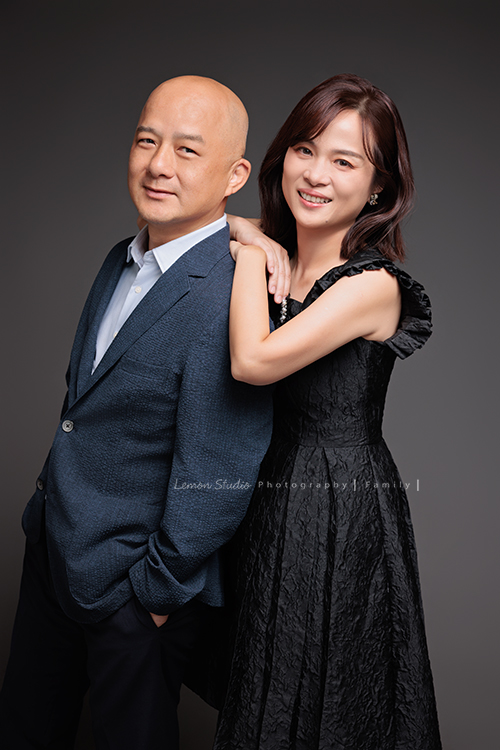 Cindy 媽麻一家來拍照，在美國念書的兒子瑋，帥氣又溫暖，一家人換上正式與休閒的服裝，每一張照片都記錄下最自然的互動與情感，這張是媽麻從爸爸後面搭著他的肩膀，兩人對著鏡頭笑得很開心的夫妻兩人的合照！