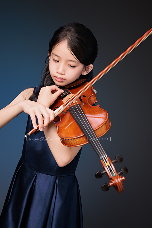 Yvonne 帶著小提琴走進鏡頭，深藍小禮服襯出她的氣質與靜謐，簡單又典雅，她不特意擺姿勢，每一張都自然又有味道，這張是Yvonne正專注地在調音的音樂寫真照！