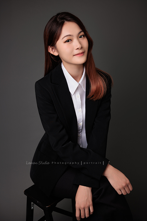 圓璽不動產專屬顧問團隊，以最真誠與專業的樣貌入鏡，每一位都展現出獨一無二的形象與風格，這是顧問妮靖坐在椅子上雙手交疊在腿上，帶著自信看著鏡頭微笑的一張不動產顧問形象照！