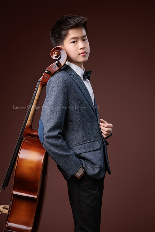 暟與大提琴，一同走進鏡頭，隨著光影與姿態變化，每一個角度，都映出暟不同的氣息與神韻，這張是暟穿上身灰色的西裝外套、側身站著背靠在大提琴上、酷酷地看著鏡頭的一張很帥氣的音樂寫真照！