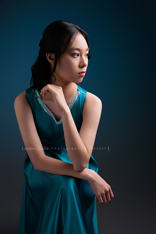 高一的珊為了即將來到的音樂會拍照，主修鋼琴的她氣質清新、表現亮眼，穿著藍色禮服的珊，舉手投足都流露出優雅與自信，這張是珊坐著頭側向一邊，沒有看鏡頭、很優雅、很有意境的一張音樂會寫真照！