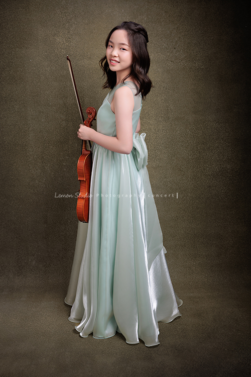 這是 Audrey 第三次來拍音樂會寫真,今年的她,又長大了一些,越來越美,也越來越有屬於自己的氣質,這張是Audrey穿著淡綠色的小禮服,一手拿著小提琴、一手拿著弓側身轉過頭來看著鏡頭微笑的一張很美的全身的小提琴音樂會寫真!