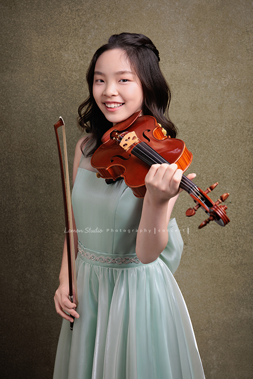 這是 Audrey 第三次來拍音樂會寫真,今年的她,又長大了一些,越來越美,也越來越有屬於自己的氣質,這張是Audrey穿著淡綠色的小禮服,一手拿著小提琴放在預備位置、一手拿著弓側身並看著鏡頭微笑的一張很美的小提琴音樂會寫真!