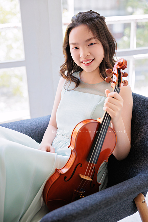 這是 Audrey 第三次來拍音樂會寫真,今年的她,又長大了一些,越來越美,也越來越有屬於自己的氣質,這張是Audrey穿著淡綠色的小禮服,坐在窗邊的椅子上一手拿著小提琴並看著鏡頭微笑的一張很美的小提琴音樂會寫真!