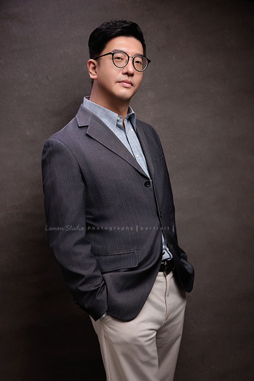 律師Kris的形象照拍攝,燈光與背景恰如其分,勾勒出他沉穩、帥氣且具質感的專業形象,這張是Kris兩手放在口袋裡,身體稍微側一些自信且微笑著看著鏡頭!