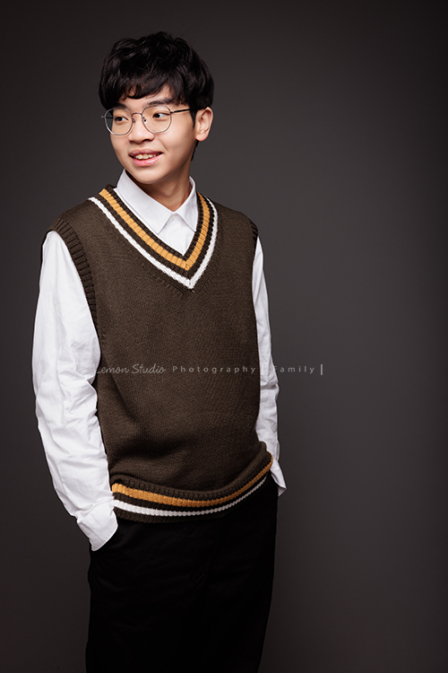 台怡媽麻和先生,帶著二十歲的兒子一起來家庭寫真,這次台怡媽麻特別準備了,三人不同顏色的帽T,這張是兒子穿著較正式的衣服站在背景前、雙手放在口袋內、沒有看鏡頭微笑的帥氣的個人寫真照!