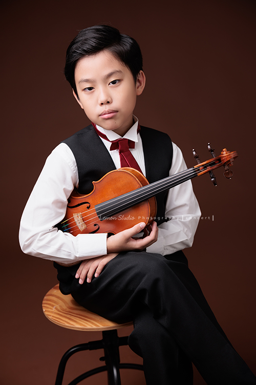 Jonathan & Chloe兄妹倆來拍提琴音樂寫真，再次站在鏡頭前，今年的 Jonathan 明顯長大了許多，Chloe非常活潑可愛，主動幫忙帶動現場氣氛，讓整個拍攝過程溫馨又美好，這張是Jonathan坐在椅子上兩手拿著提琴、酷酷地看著鏡頭的音樂寫真照！