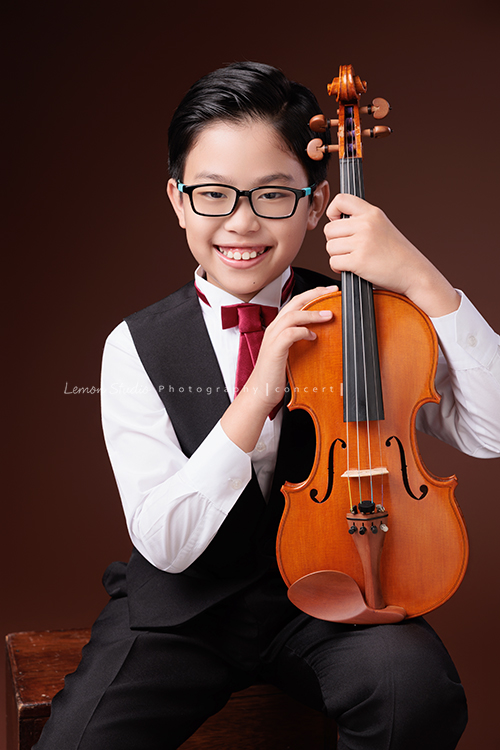 Jonathan & Chloe兄妹倆來拍提琴音樂寫真，再次站在鏡頭前，今年的 Jonathan 明顯長大了許多，Chloe非常活潑可愛，主動幫忙帶動現場氣氛，讓整個拍攝過程溫馨又美好，這張是隔了一年長大許多的Jonathan，Jonathan坐著兩手拿著提琴、看著鏡頭笑得很開心的一張音樂寫真照！