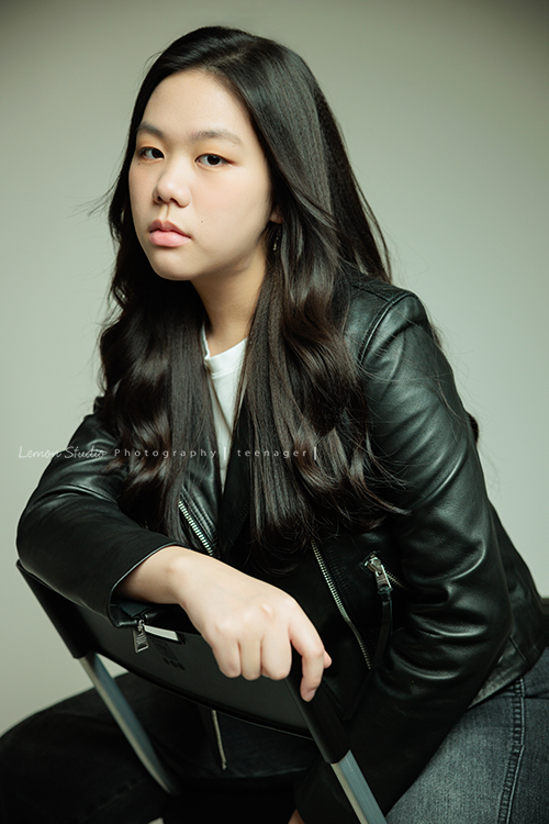 Audrey也是從小到大來拍過幾次照的孩子，隨著時間過去她也悄悄長大了啊，在高中這個階段，為她留下紀錄，這張是Audrey坐在椅子上一手放在椅子上、一手放在大腿上、很酷地看著鏡頭的很有時尚感的高中女孩寫真照！