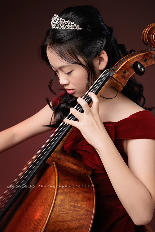 音樂班的Yuko即將畢業，帶著她的大提琴來到鏡頭前，在不同的禮服與不同的樂器之間，看見不一樣的她，這張是Yuko身穿一襲紅色禮服、在紅色背景前坐在椅子上、低頭很專心地拉著大提琴的音樂班畢業音樂寫真！