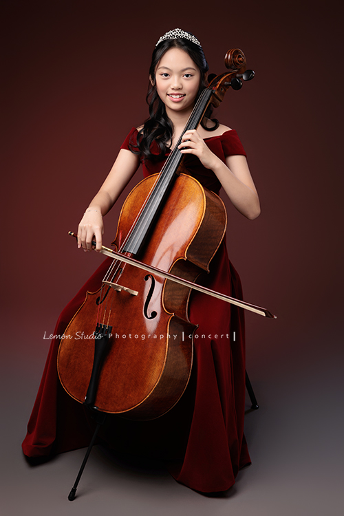 音樂班的Yuko即將畢業，帶著她的大提琴來到鏡頭前，在不同的禮服與不同的樂器之間，看見不一樣的她，這張是Yuko身穿一襲紅色禮服、在紅色背景前坐在椅子上、手正拉著大提琴、看著鏡頭微笑的音樂班畢業音樂寫真！