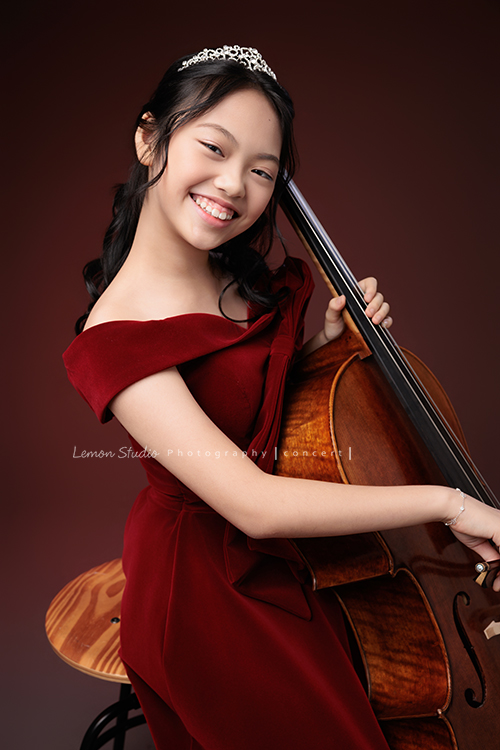 音樂班的Yuko即將畢業，帶著她的大提琴來到鏡頭前，在不同的禮服與不同的樂器之間，看見不一樣的她，這張是Yuko身穿一襲紅色禮服、在紅色背景前側坐在椅子上、手正拉著大提琴、看著鏡頭笑容很燦蘭可愛的音樂班畢業音樂寫真！