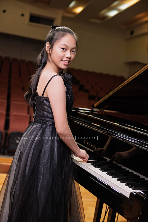 音樂班的Yuko即將畢業，帶著她的大提琴來到鏡頭前，在不同的禮服與不同的樂器之間，看見不一樣的她，這張是Yuko身穿一襲黑色禮服、站在演奏廳的大鋼琴前、側身轉過頭來看著鏡頭微笑的一張很有氣質的音樂班畢業音樂寫真！