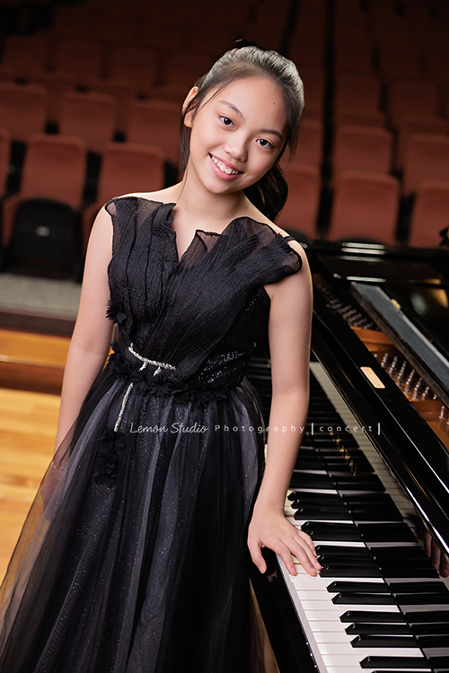 音樂班的Yuko即將畢業，帶著她的大提琴來到鏡頭前，在不同的禮服與不同的樂器之間，看見不一樣的她，這張是Yuko身穿一襲黑色禮服、站在演奏廳的大鋼琴前、一手在琴鍵上、看著鏡頭微笑的一張很有氣質的音樂班畢業音樂寫真！