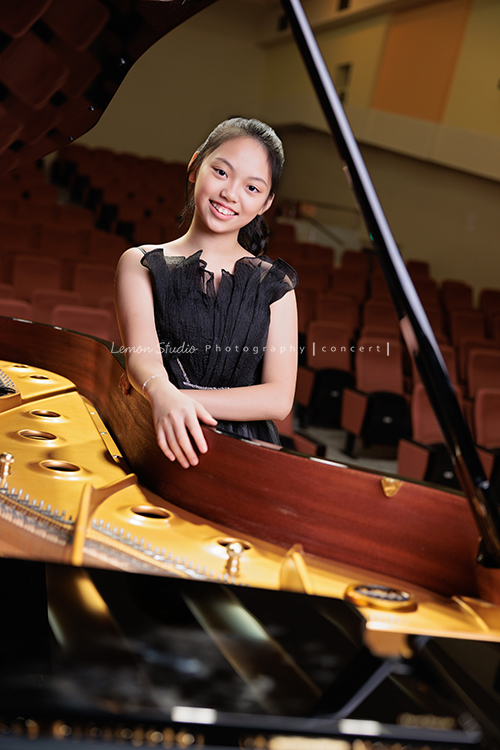 音樂班的Yuko即將畢業，帶著她的大提琴來到鏡頭前，在不同的禮服與不同的樂器之間，看見不一樣的她，這張是Yuko身穿一襲黑色禮服、站在演奏廳的大鋼琴前、雙手放在鋼琴上、看著鏡頭微笑的一張很有氣質的音樂班畢業音樂寫真！