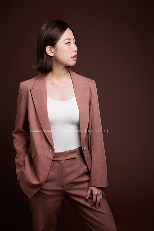 體態管理師大妞來拍形象照,她穿上一襲帶著咖啡暖色調的套裝,站在鏡頭前的她很自然且從容,這張是大妞站著一手自然地擺放在身旁、一手放在口袋裡、眼鏡看向側方、是一張很有質感及意境的形象照!