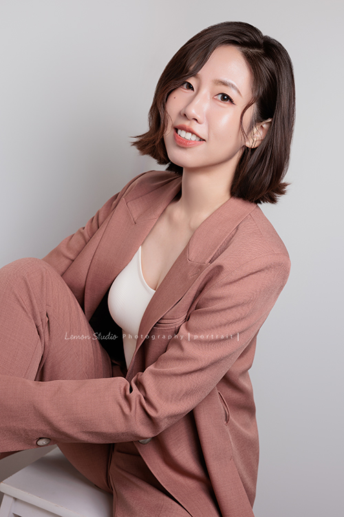 體態管理師大妞來拍形象照,她穿上一襲帶著咖啡暖色調的套裝,站在鏡頭前的她很自然且從容,這張是大妞坐著兩手放在腳上,看著鏡頭微微地笑著的一張很有質感的形象照!