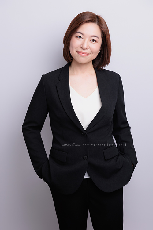 很榮幸再次為充滿幸福感的企業拍攝內部人員的形象照，這次拍了許多不同的部門的成員，企業形象照在無形之中，也為公司整體的形象與質感，多添了一份專業與信任感，這張是企業內部的一位女職員穿上黑色的外套、雙手放在口袋裡，微笑地看著鏡頭的一張很有質感的形象照！