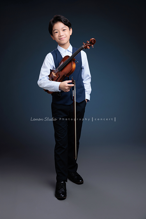 喆即將從國小弦樂團畢業，和同學們一起來拍音樂寫真照，拍照當天在現場很認真地拉琴，我們也不知不覺成了他的粉絲，這張是喆一手拿著提琴、一手放口袋，看著鏡頭沈穩且有自信地微笑著的一張全身的音樂寫真照！