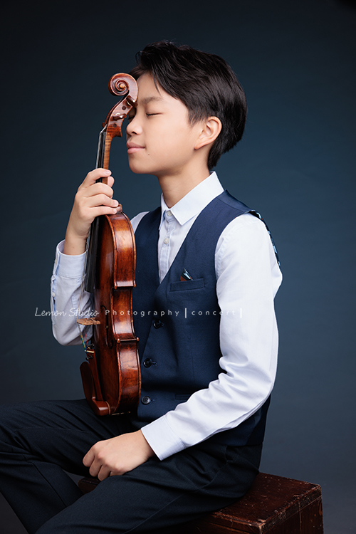 喆即將從國小弦樂團畢業，和同學們一起來拍音樂寫真照，拍照當天在現場很認真地拉琴，我們也不知不覺成了他的粉絲，這張是喆坐著提琴在身體前方、喆一手扶著提琴、閉著眼睛且頭輕輕靠在提琴上、是一張很有意境的音樂寫真照！