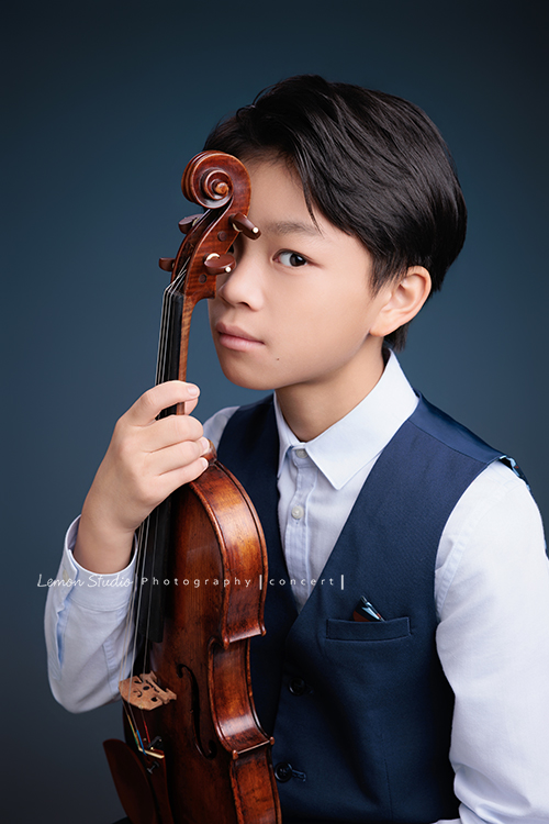 喆即將從國小弦樂團畢業，和同學們一起來拍音樂寫真照，拍照當天在現場很認真地拉琴，我們也不知不覺成了他的粉絲，這張是喆坐著提琴在身體前方、喆一手扶著提琴、頭輕輕靠在提琴上、很沈穩且酷酷地看著鏡頭、是一張很有意境且帥氣的音樂寫真照！