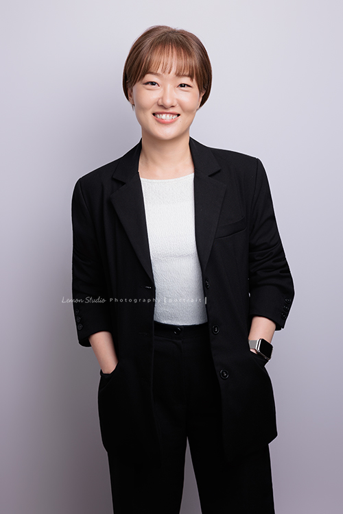 很榮幸再次為充滿幸福感的企業拍攝內部人員的形象照，這次拍了許多不同的部門的成員，企業形象照在無形之中，也為公司整體的形象與質感，多添了一份專業與信任感，這張是企業內部的一位女職員穿上黑色外套、雙手放在口袋裡，微笑地看著鏡頭的一張很有質感的形象照！