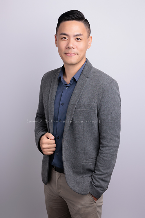 很榮幸再次為充滿幸福感的企業拍攝內部人員的形象照，這次拍了許多不同的部門的成員，企業形象照在無形之中，也為公司整體的形象與質感，多添了一份專業與信任感，這張是企業內部的一位男職員穿上灰色的西裝外套、一手放在口袋、一手抓著外套，微笑地看著鏡頭的一張很有質感的形象照！